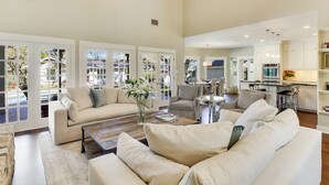 A spacious living room with a large sofa, a coffee table, and a dining area with chairs. - Above Auth Westlake I Pool I Hot Tub I Game Room I Back House I Greenbelt (West Lake Hills)