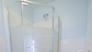 A bathroom with a glass shower enclosure, a toilet, and a white rug on the floor. - Whitehall Cottages Boutique Motel - Full Bed (Whitehall)