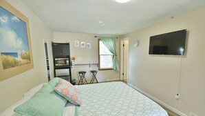A bedroom with a bed, a TV, a window with curtains, a desk, and a bunk bed. - Whitehall Cottages Boutique Motel - Full Bed (Whitehall)