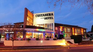 The exterior of the Costanera Hotel with a prominent sign, a bar named Cafe de la Costa, and a Heineken logo. - Hotel Costanera (Villa Carlos Paz)