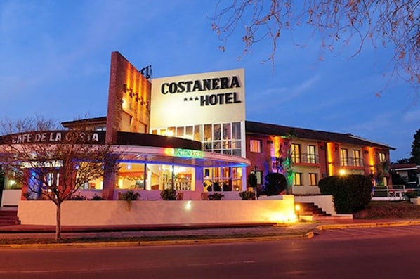 El exterior del Hotel Costanera, con un letrero destacado, un bar llamado Cafe de la Costa y el logotipo de Heineken.