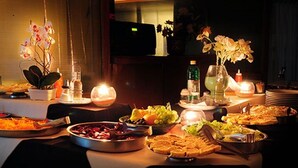 A buffet table with various food items and drinks, lit by candles. - Hotel Costanera (Villa Carlos Paz)