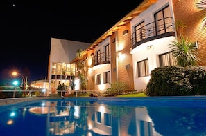 Un hotel moderno con piscina, fachada bien iluminada y arquitectura que combina ladrillo y vidrio.