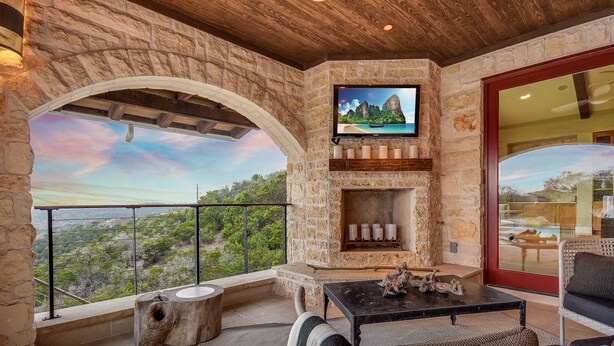 Una chimenea de piedra con un televisor encima, mobiliario para exteriores y una vista panorámica.
