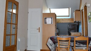Una cocina compacta con ventana, una mesa de comedor con sillas y una puerta blanca.