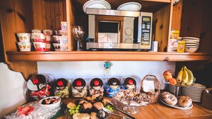 A kitchen counter with various food items, a microwave, and a coffee maker. - Roanoke Island Inn (Manteo)