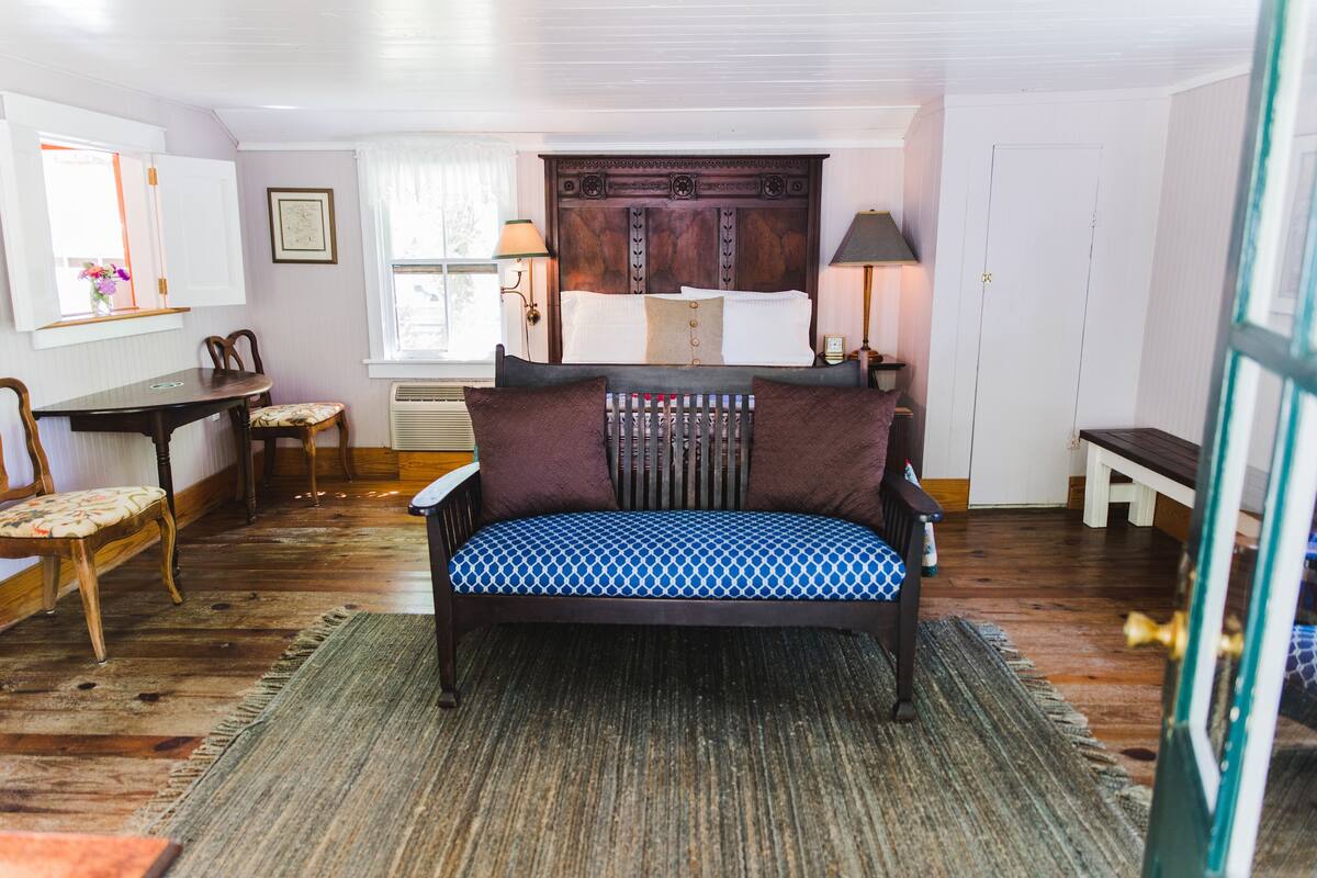 Una habitación con una cama, una silla, una mesa y una lámpara.