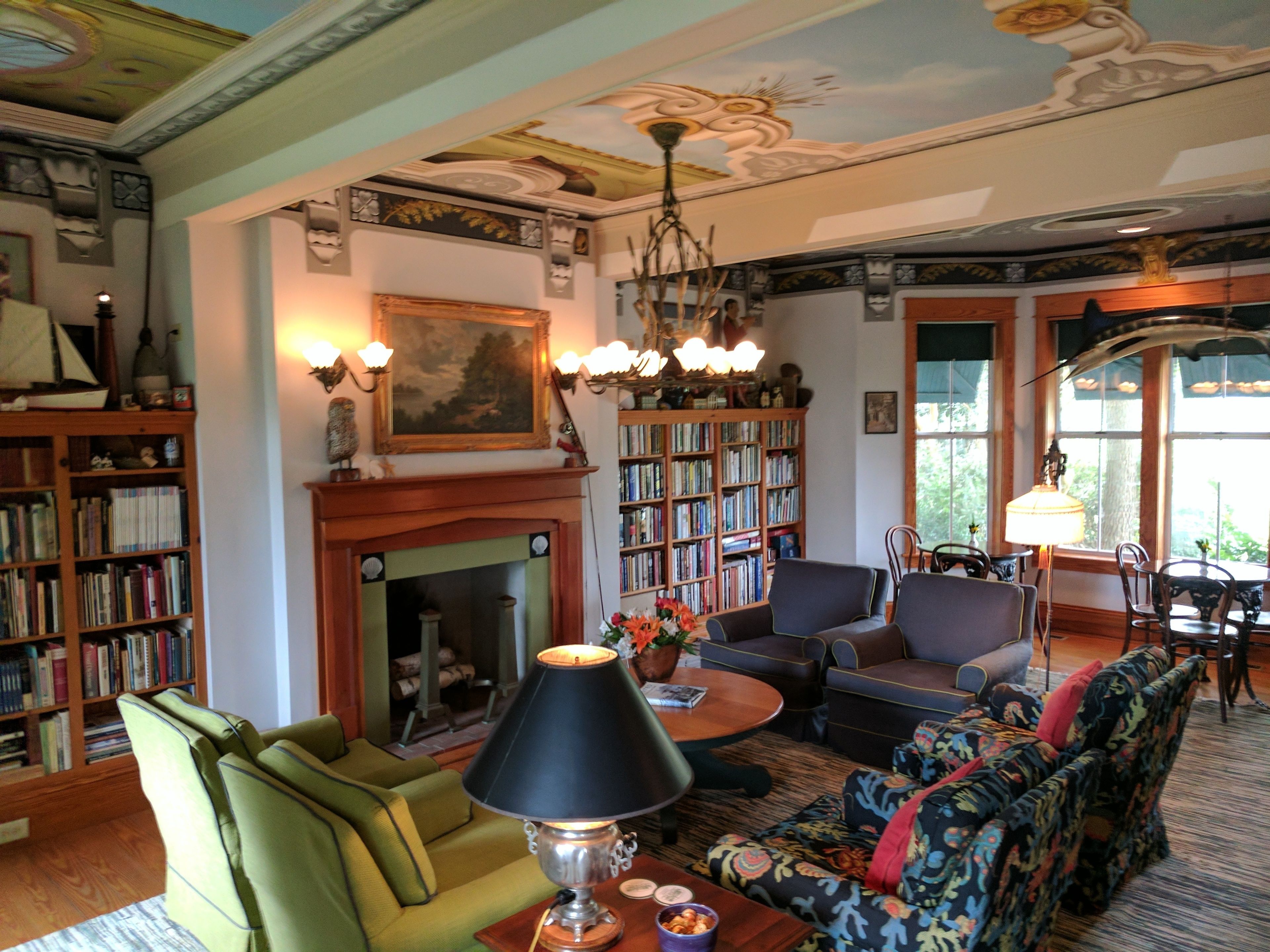 A cozy living room with a fireplace, bookshelves, a sofa, and a lamp.
