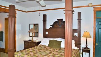 A bedroom with a four-poster bed, wooden headboard, and a ceiling fan.