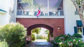 Un bâtiment à deux étages doté d’une entrée en arc de briques, d’un balcon avec des balustrades et d’un drapeau.
