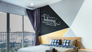 Een moderne hotelkamer met een groot bed, uitzicht over de stad en een inspirerende muursticker.