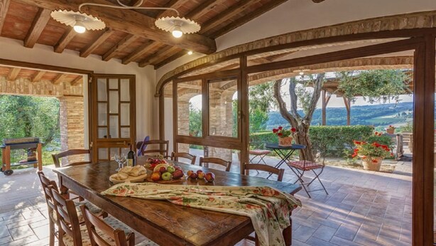 Uma área de refeições rústica com uma mesa de madeira, cadeiras e vista para o exterior.