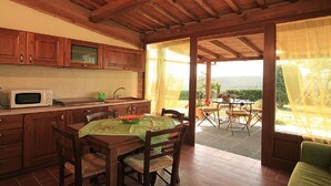 Cozinha com armários de madeira, micro-ondas e área de jantar com mesa e cadeiras.