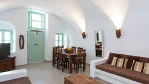 Un vaste espace de vie comprenant une table à manger, des chaises en bois, un canapé et un téléviseur.