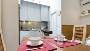 Un coin repas avec une table en bois dressée pour deux personnes, un set de table rouge, un bol blanc et des verres.