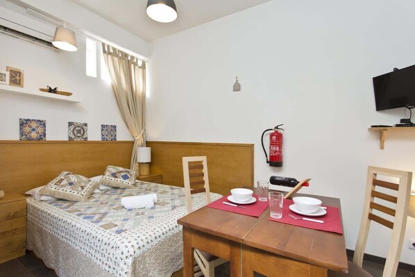 Une chambre d’hôtel comprenant un lit, une table à manger avec des chaises, un téléviseur et un extincteur.