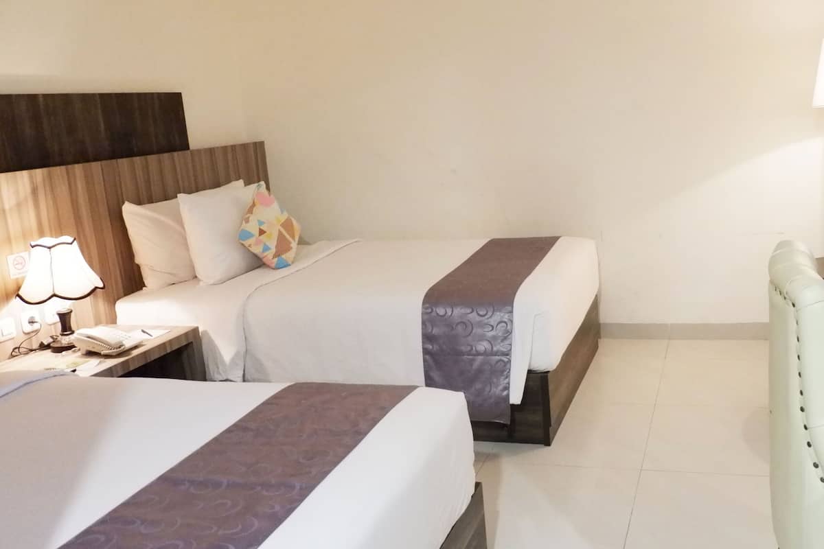 A hotel room with two beds, a TV, a desk with a lamp, and a chair.