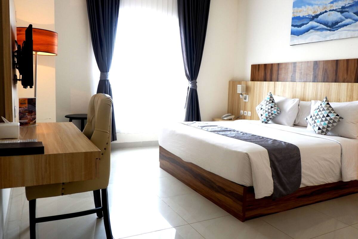 A hotel room with a wooden bed frame, a desk, and a chair.