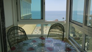 A balcony with a table and chairs, overlooking a beach with umbrellas and people. -  Wonderful view of the beach and river,  front line with garage T2. 1978 / AL (Praia da Rocha Portimão)
