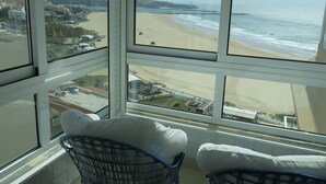 A room with large windows overlooking a beach and a coastal town. -  Wonderful view of the beach and river,  front line with garage T2. 1978 / AL (Praia da Rocha Portimão)