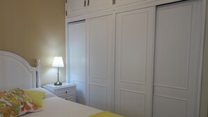 A bedroom with a bed, a nightstand with a lamp, and a wardrobe. -  Wonderful view of the beach and river,  front line with garage T2. 1978 / AL (Praia da Rocha Portimão)