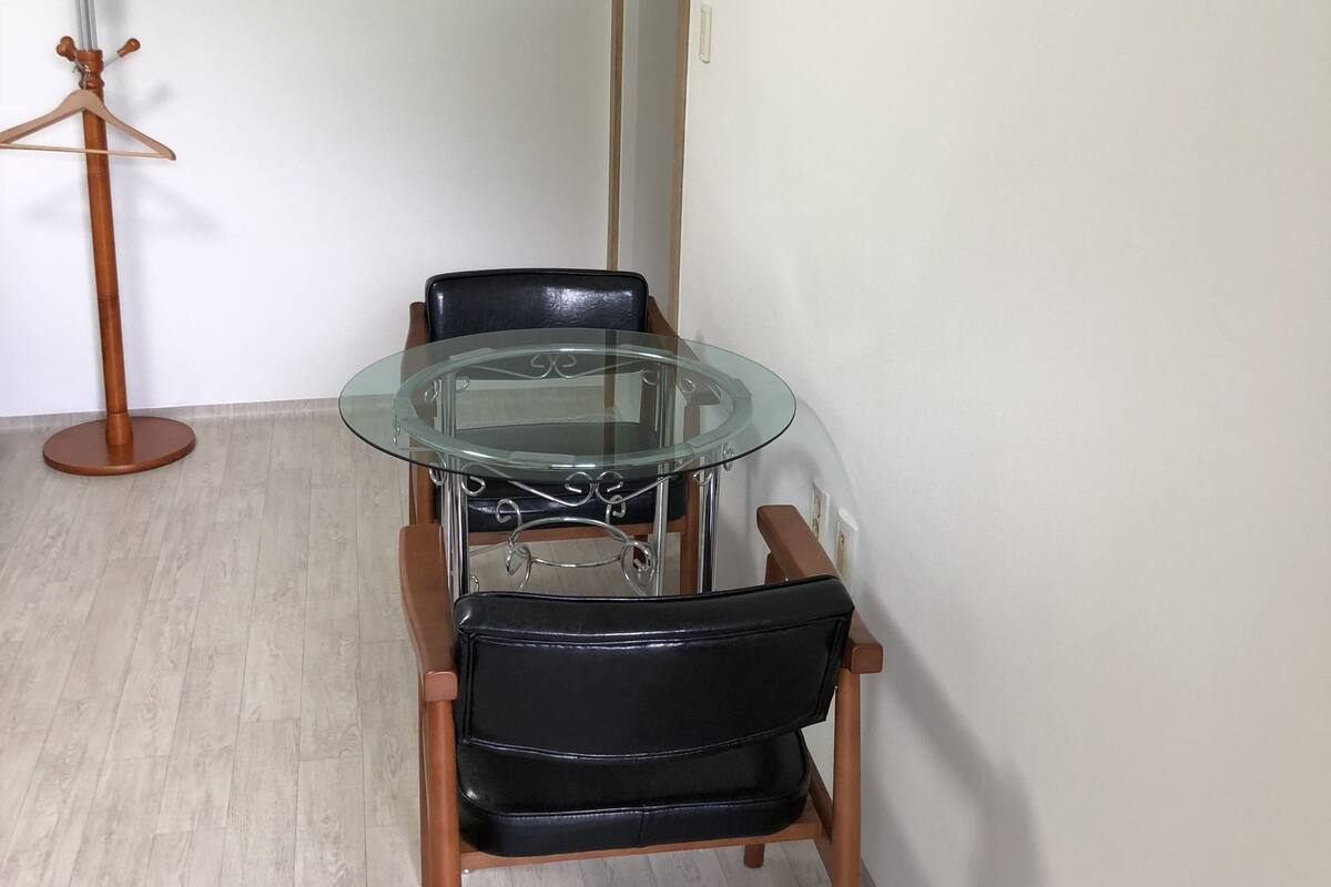 A dining area with a glass-top table and two black chairs.