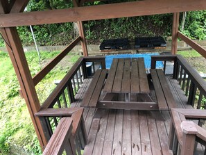 A wooden deck with picnic tables and a blue tiled area in the background. - Izmir Pension (Gangneung)