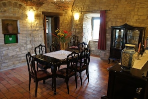 Une salle à manger rustique avec un mur en pierre, une table en bois et des chaises.