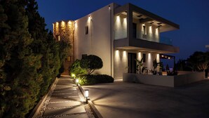 A modern two-story house with a stone facade and a well-lit entrance. - Orama Luxury Villa, 4 Bedrooms with Private Pool, Sleeps 8 (Piskopiano)