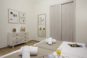 A hotel room with a bed, a bedside table with a glass of orange juice, a white dresser, and a mirror. - Singular Stays Seu II (Valencia ciudad)