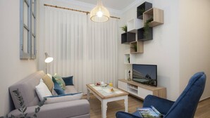 A modern living room with a sofa, a coffee table, a TV, and a blue armchair.