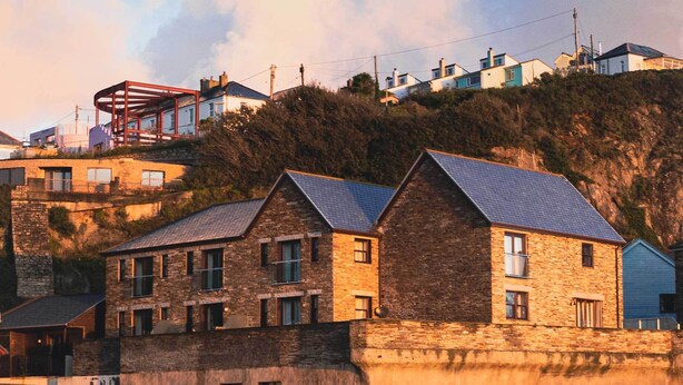 A coastal building with a stone facade, multiple windows, and a metal roof. - Delightful home with balcony overlooking the sea. Easy access, Free car park (MEVAGISSEY, Cornwall)