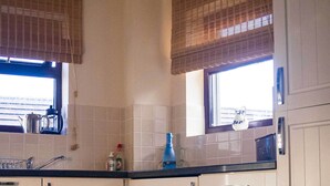 A kitchen with white cabinets, a black countertop, and a window with blinds. - Delightful home with balcony overlooking the sea. Easy access, Free car park (MEVAGISSEY, Cornwall)