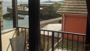 A balcony with a view of a lighthouse and rocky coastline. - Delightful home with balcony overlooking the sea. Easy access, Free car park (MEVAGISSEY, Cornwall)