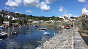 A harbor with boats docked, a stone quay, and buildings in the background. - Delightful home with balcony overlooking the sea. Easy access, Free car park (MEVAGISSEY, Cornwall)