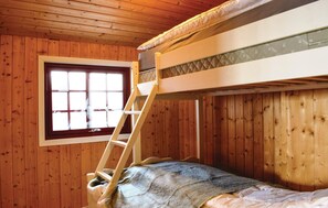 Ein Schlafraum mit Etagenbetten, Holzwänden, einem Fenster und einer Leiter.