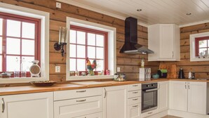 A kitchen with wooden walls, white cabinets, and a large window with a rooster decoration.