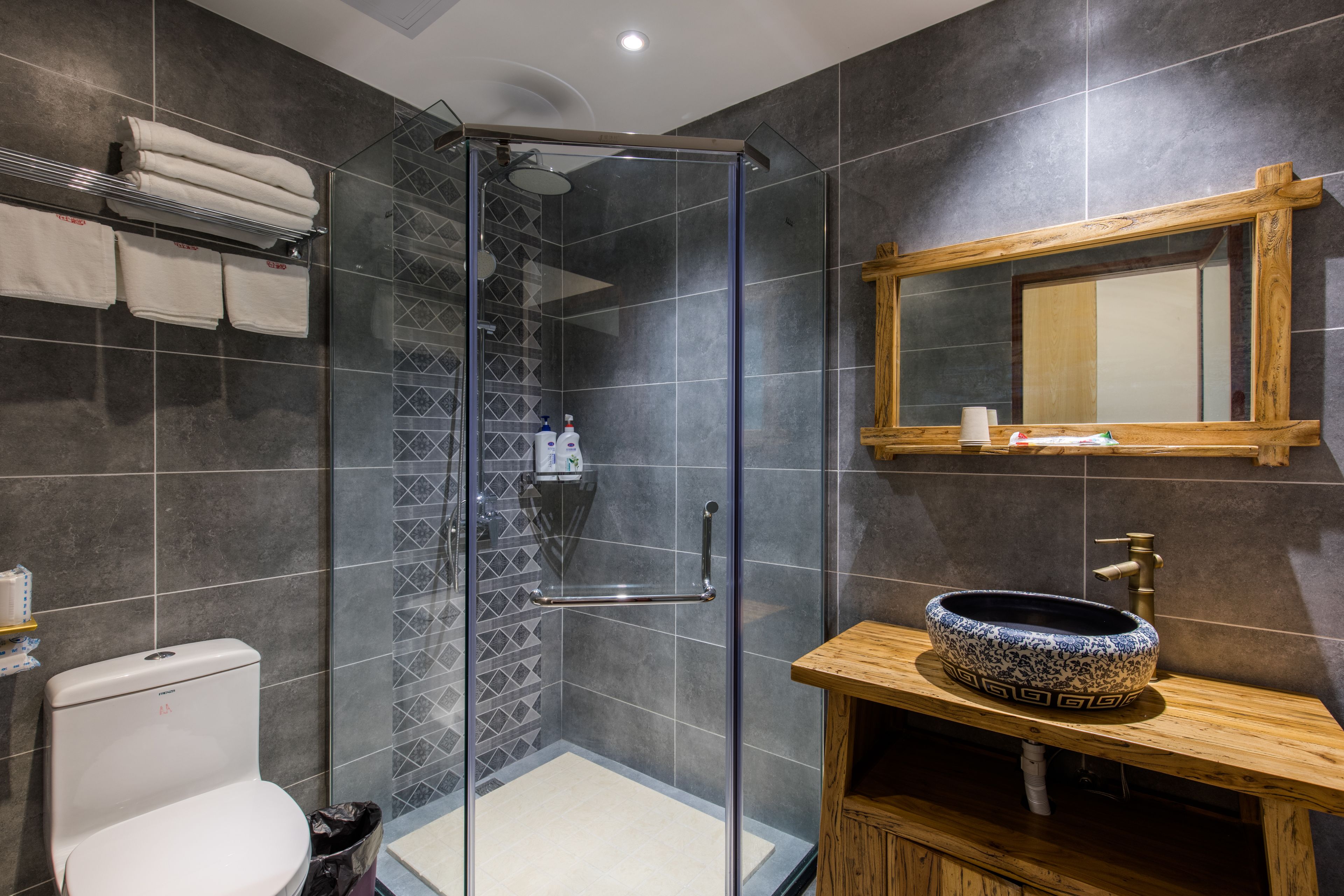 A modern bathroom with a glass-enclosed shower, a wooden vanity with a decorative sink, and a tiled shower area.