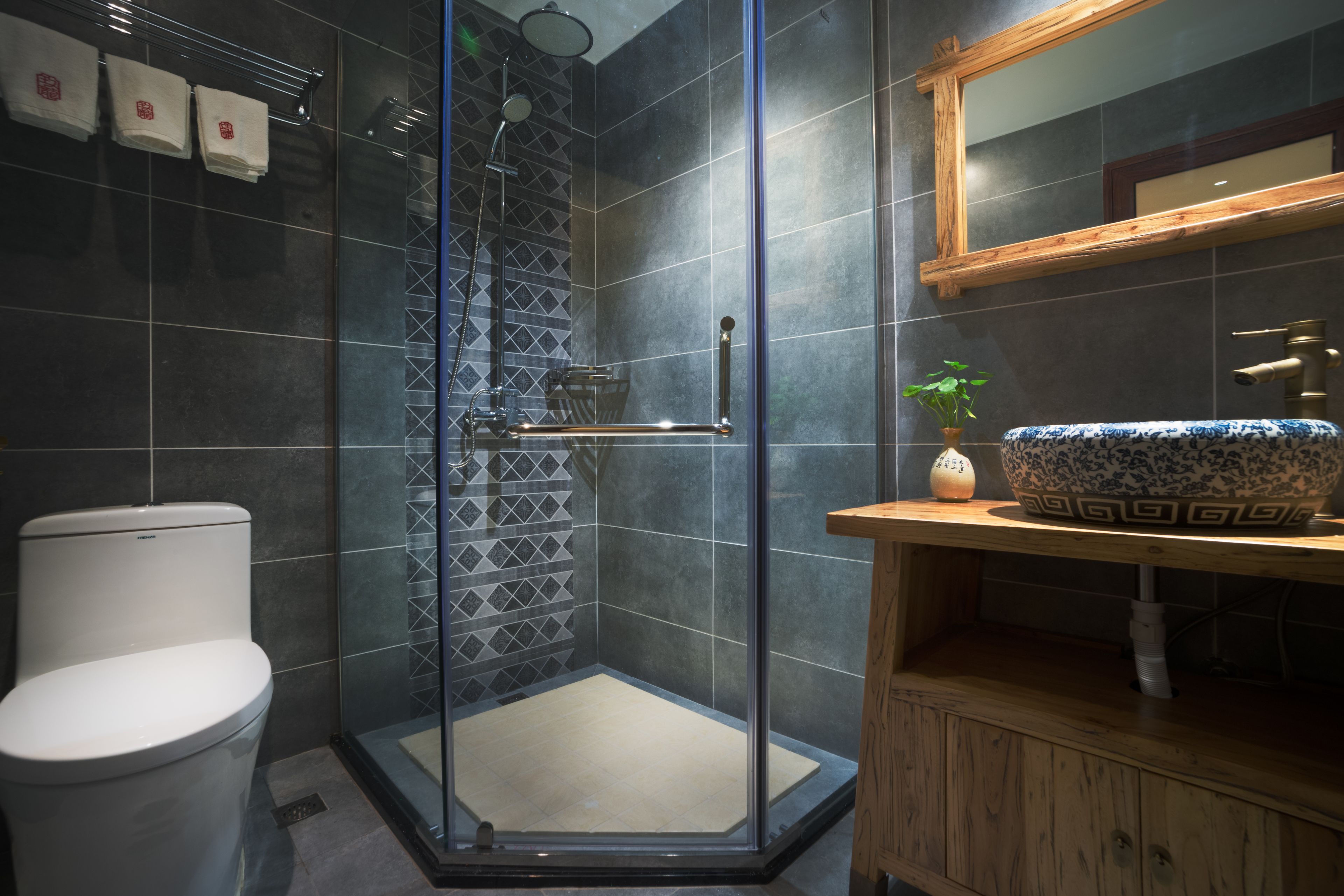 A modern bathroom with a glass-enclosed shower, a white toilet, and a wooden vanity with a patterned sink.