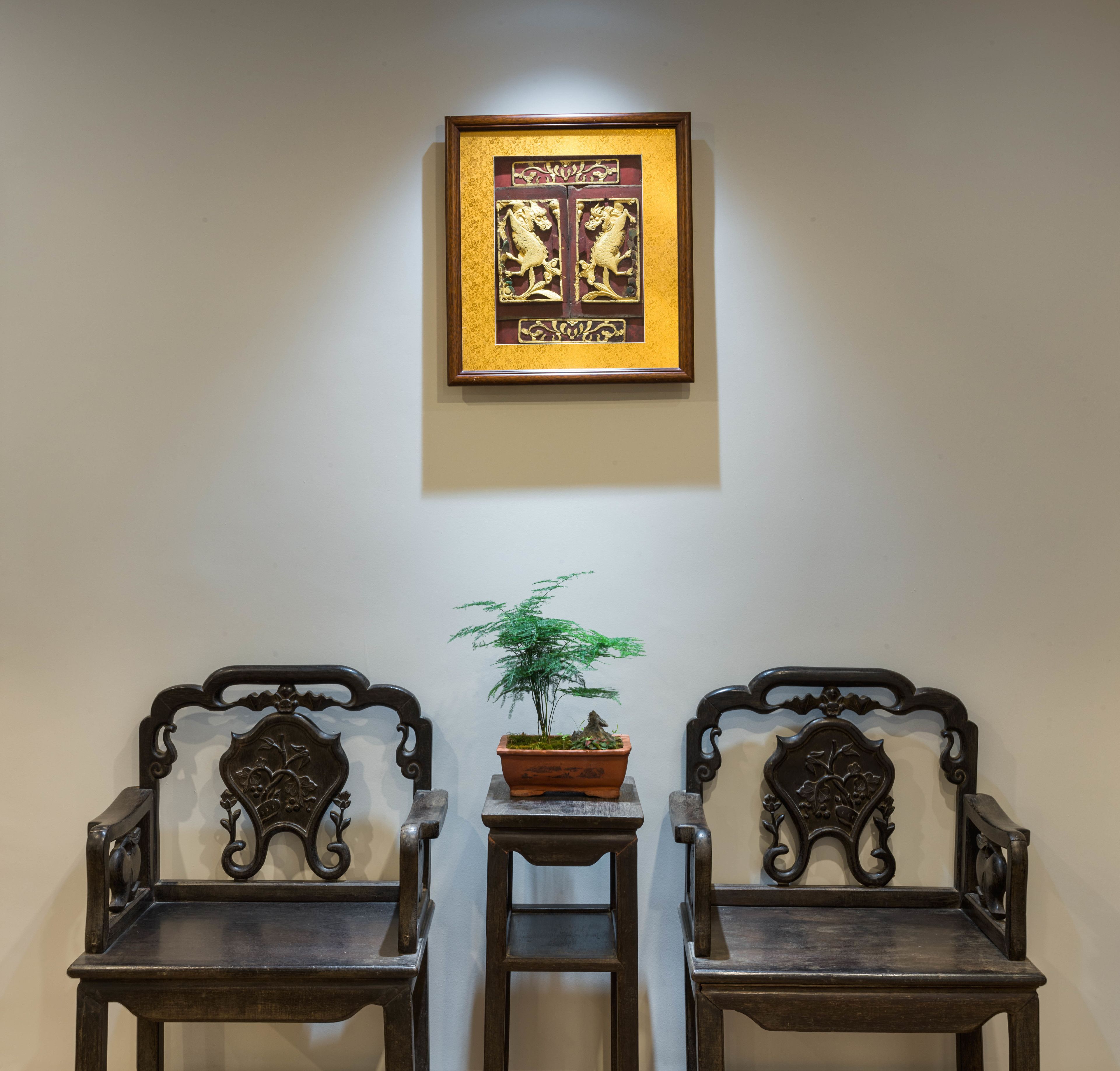 Two ornate wooden chairs with a small table and a potted plant between them.