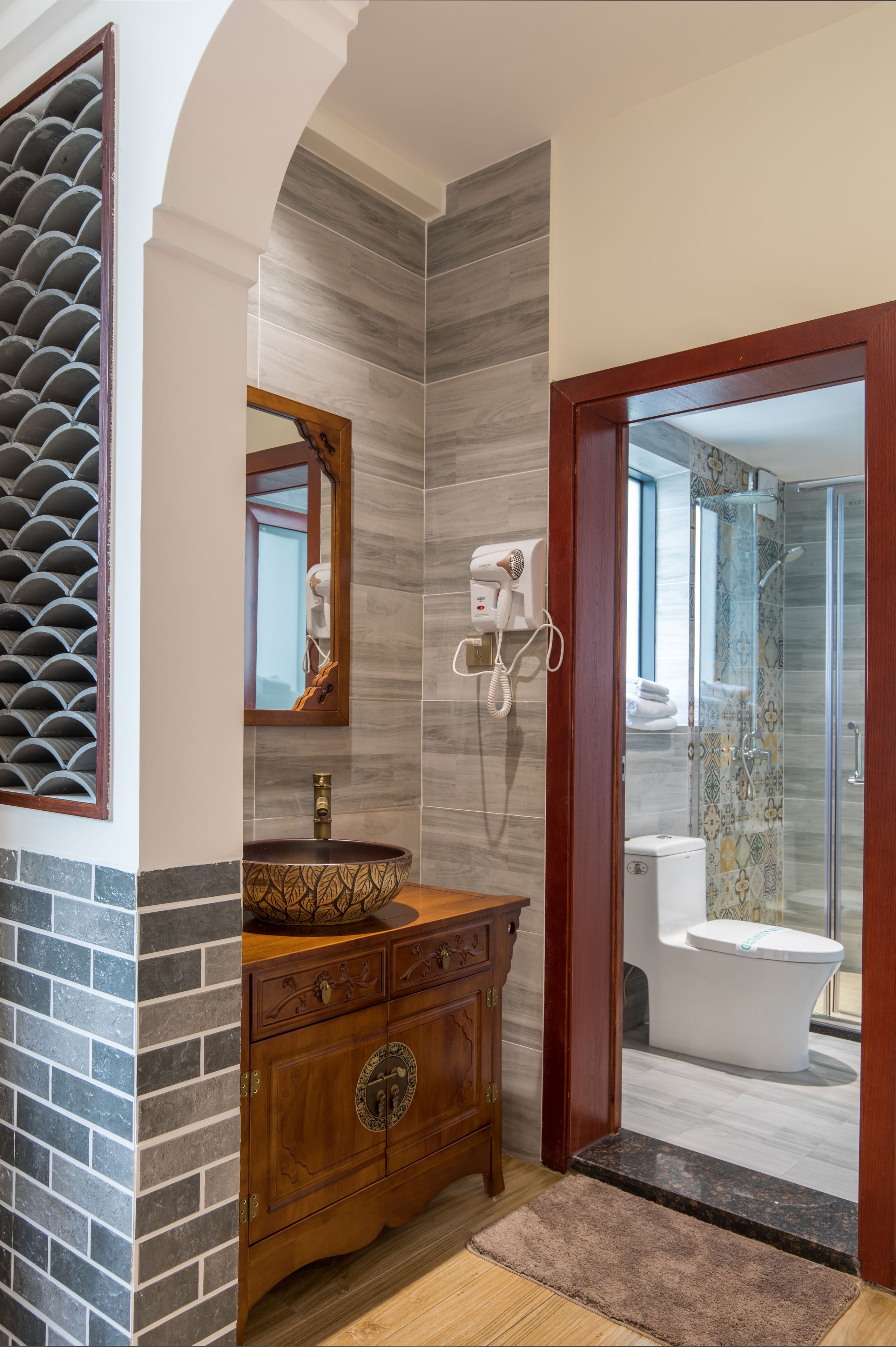 A bathroom with a wooden vanity, a mirror, a hairdryer, and a toilet.