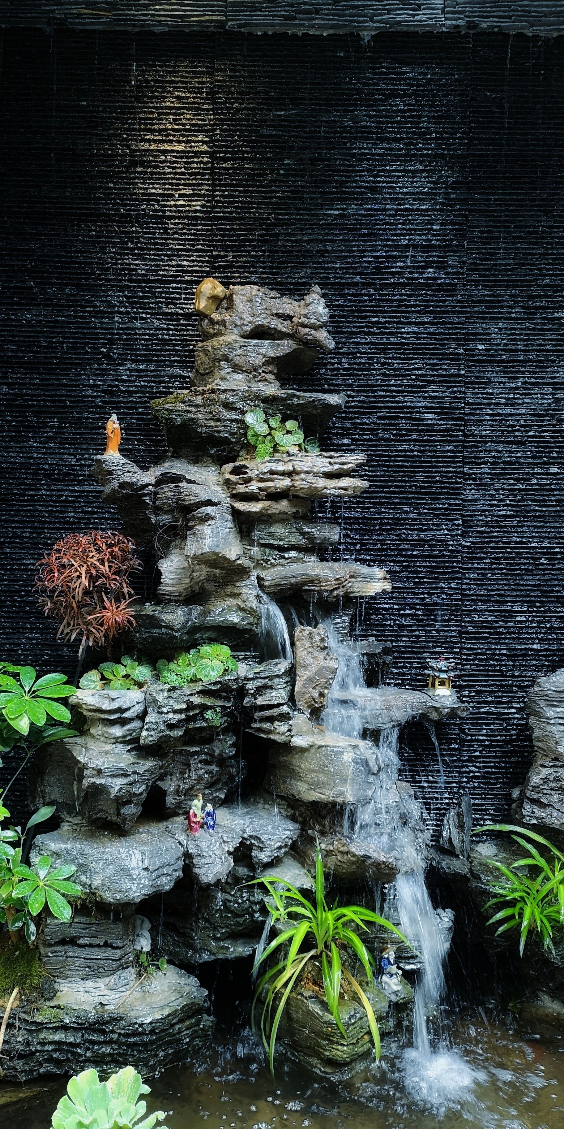 Una cascada de rocas con estatuas y plantas.