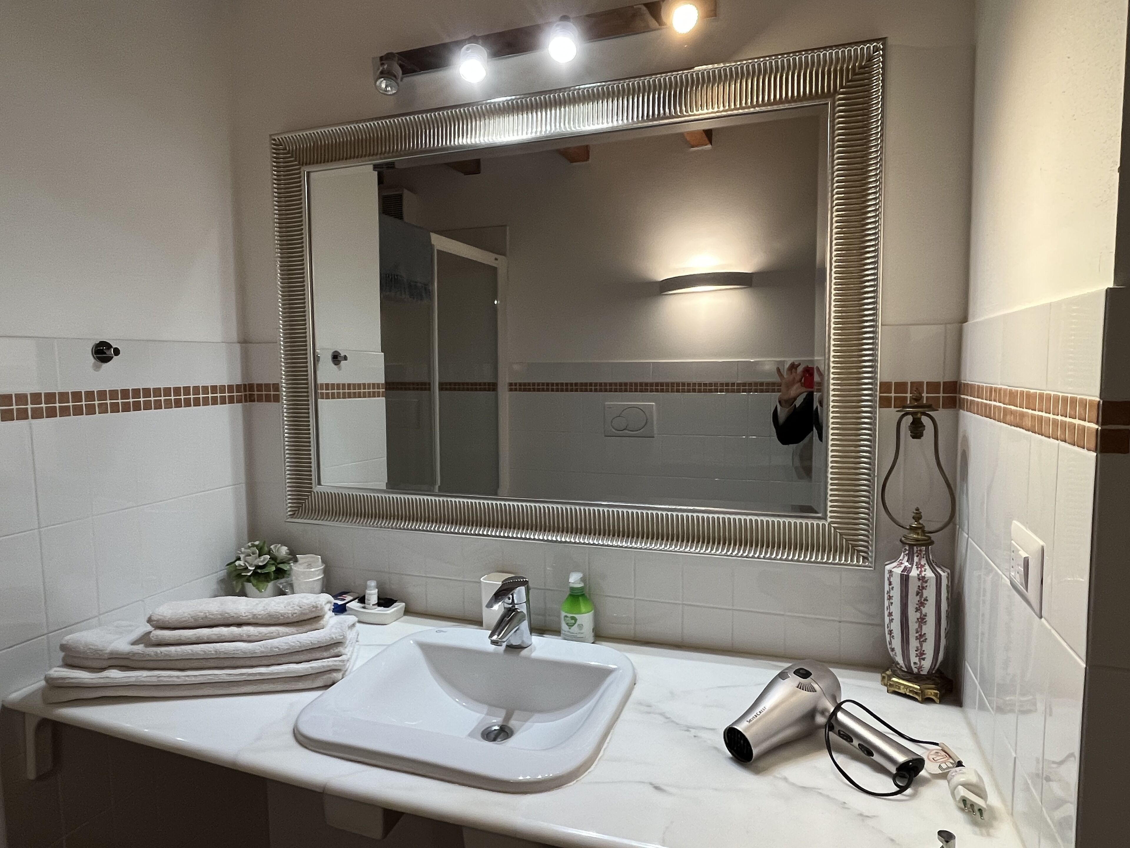 A bathroom with a large mirror, a sink, a towel rack, and a hairdryer.