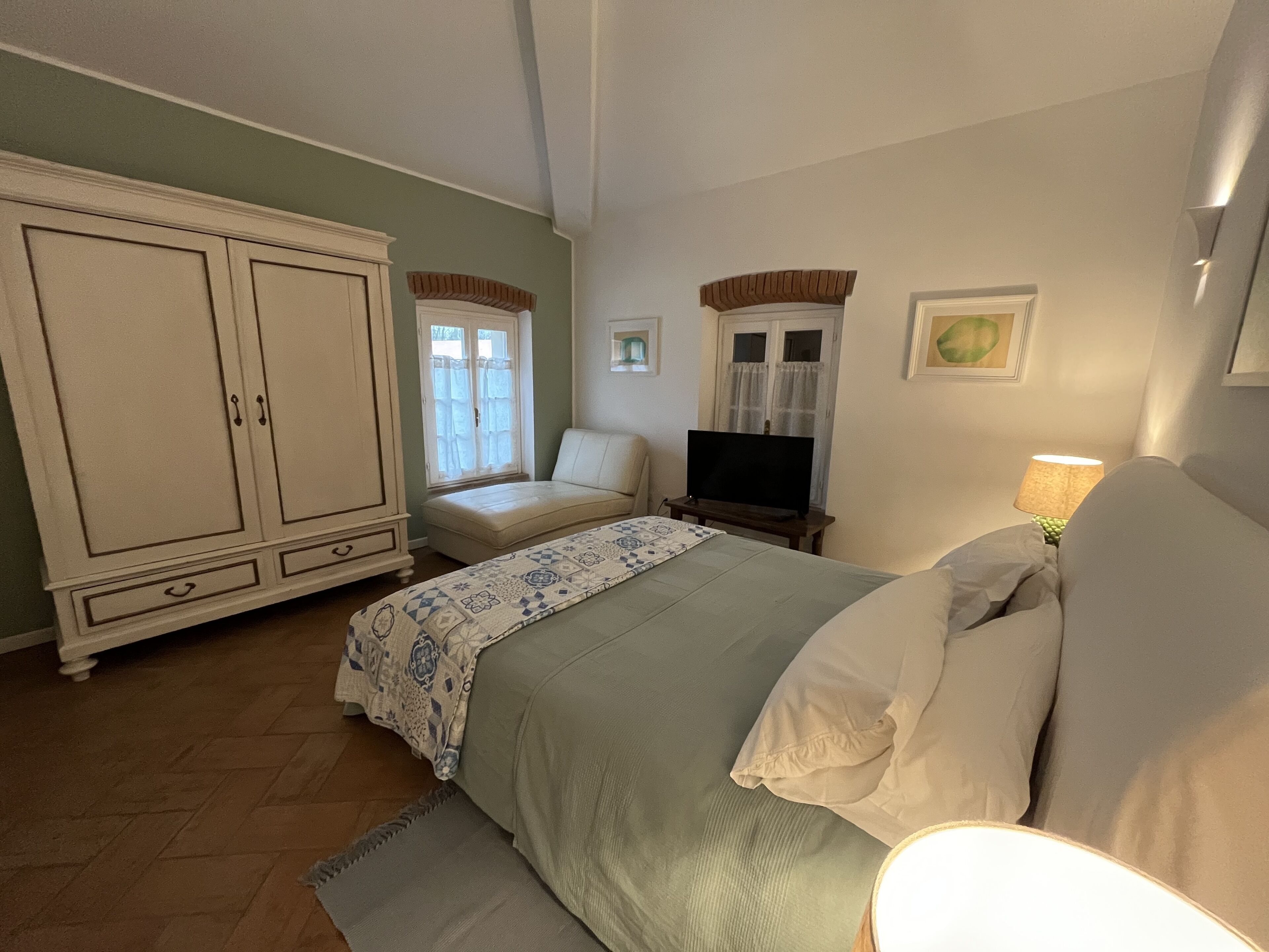 Una camera da letto con un letto, una televisione, un armadio e una finestra con tende.