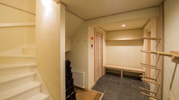 A hallway with a wooden bench, a radiator, and a door with a red light.