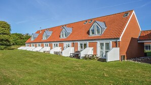 Une rangée de bâtiments d’un seul étage, avec des toits recouverts de tuiles rouges et des fenêtres à cadre blanc, qui semblent être une résidence ou une propriété de vacances.