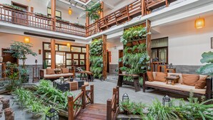 Een ruime binnentuin met houten hekwerk, zitgedeeltes en volop groen.