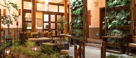 A lobby with a wooden staircase, a sofa, and various potted plants.