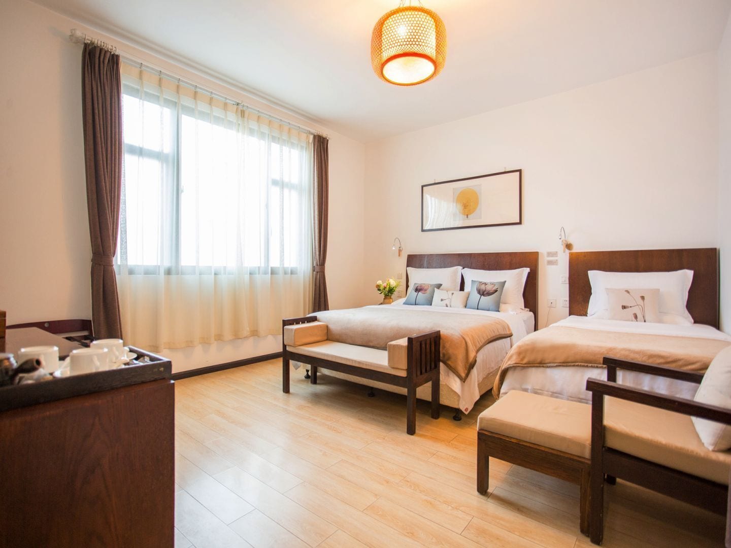 Una habitación de hotel con dos camas, un escritorio de madera y un ventanal con cortinas.