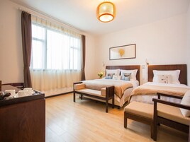 Una habitación de hotel con dos camas, un escritorio de madera y un ventanal con cortinas.